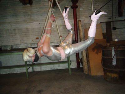 Superheroine gets a flying lesson The Hunter has captured spandex clad crime fighter Lauri Adverb as she trespassed in his lair. She now hangs by her wrists from a rope attached to some overhead pipes in a c ruel strappado. Screaming and cursing, defiant Lauri pulls at the ropes struggling to break free. The Hunter returns and stuff socks into her mouth to shut her up then wraps layers of vet wrap around her head stifling her screams. She kicks at him as he finishes the gag and he grabs her booted ankle. He ties a rope around her ankle and then lifts her foot high in the air behind her and attaches the rope to the overhead pipes. Lauri is up onto her toes on her other foot. He then ties a tight crotch rope between her legs and attaches the crotch rope to the overhead pipes. Lauri's other foot barely makes contact with the floor now as she is almost completely suspended by her wrists, ankle and crotch. The Hunter then ties a rope to her other ankles and lifts that one up as well and ties it to the pipes over her head. Lauri hangs in the air with her poor shoulders screaming in agony from bearing most of her weight. She twists and turns struggling to pull free from the ropes but there is no escape as the Hunter leaves his hapless victim hanging from the pipes. <br><br><span style='color:#b0b0b0;'>[隐藏文字，购买后可见]</span>