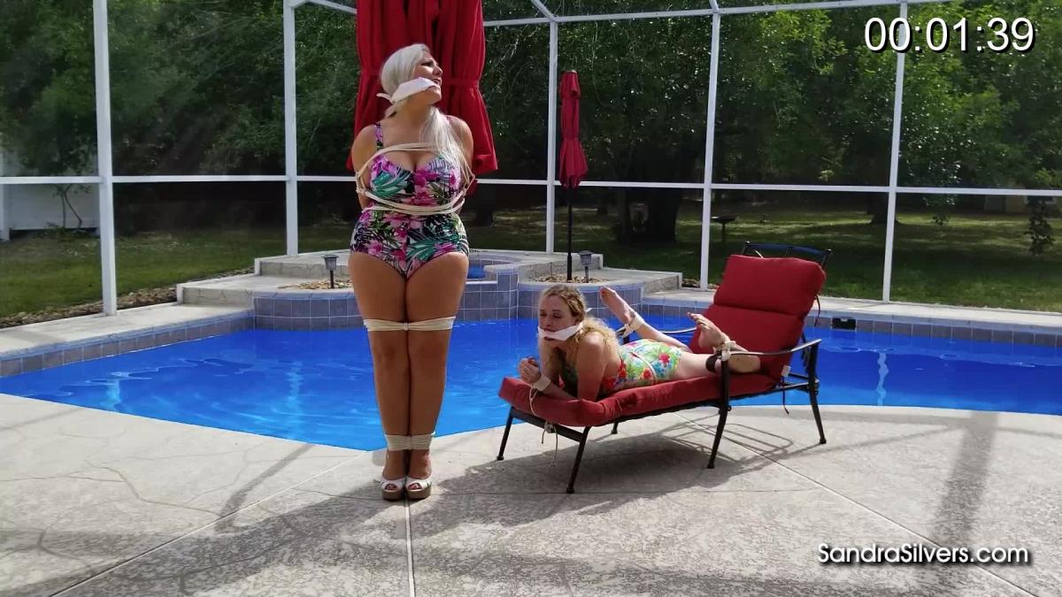 2900 Sandra Silvers and Lauren Kiley Tied by the Pool Guy, Swimsuited Damsel Duo - Pole-tied and Hogtied - Struggle in the Sun!<br><br>It's a sweltering hot day and the sun beats down on Sandra and Lauren mercilessly, but tied as they are, the refreshing water of the pool remains tantalizingly out of the bathing suited beauties reach. The pool guy carries on about his business, for he knows they won’t be going anywhere till he’s done. Enjoying the sound of the waterfall gently splashing, the birds singing in the trees of the large garden behind, and the insistent MMMphing of the trussed up two in front of him. Enjoying the view of ample curves of Sandra the buxom MILF poured into a swimsuit and pole tied to the sunshade umbrella, the long legs and arching dancers feet  of Lauren, hogtied on the chaise sun lounger. It’s a good life.
