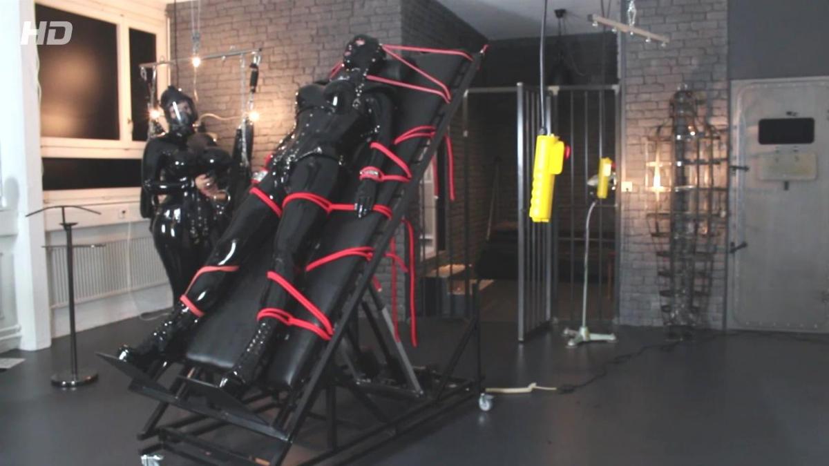 Bondage Helmet - Part 4 This week I was with Comtesse Larissa at then new and really awesome equipped new dungeon in Zürich, Switzerland, called "Der FemDOM". We give our visits mostly some pervy name and so we called it this time "Rubber Mania" and finally this was also on the schedule...<br><br>… we arrived monday morning in Zürich and started to unpack fastly our luggage and rubber because we were really short on time and had to rubberize ourselves and prepare everything for the session. I helped first Comtesse Larissa into the big boobed catsuit and so it happened that we already find ourselves while dressing up in the session, even if the guest wasn’t still in the dungeon.<br><br>I was dressed in my black lockable rubbercatsuit and as always I had to rubberize my crotch in a really pervy style. After that I was laced first into a black COR13 corset from HW-Design and another rubberpussy was attached between my legs. Double rubberpussy! This was even new to me too  but the feeling was incredible sexy and horny.<br><br>The real thing started after the corset. The Bondage Helmet. An integrated heavy rubber mask and neck corset, which can be added to the straps of the COR13 corset. It laces from top of the head to the complete end of the bondage helmet is therefore very restrictive and tight. Larissa had certainly a lot of fun squeezing my head into this rubber head prison and strapping it to the corset then.<br><br>She watched on her work and let me turn one time to see the complete beauty of this restrictive outfit. Then she started to rub my double rubberized pussy in my crotch, when she realized that the guest has written a SMS telling that he will be 2 hours late because of heavy traffic jam. This was the moment, when Larissa became a horny and breathtaking plan. She put me for this time into the gibbet cage. Fully laced and corseted as I was, I was put into this almost tight and unbreakable metal stand prison…